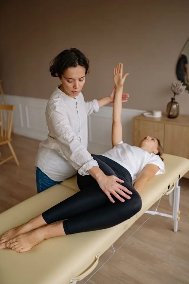 A physiotherapist guiding a patient through a shoulder stretch during a home visit